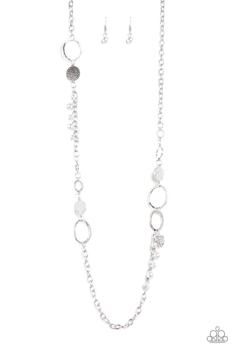 Paparazzi Accessories Unapologetic Flirt - Silver Infused with sections of shimmery silver chains, an assortment of hammered silver discs and silver rings link across the chest. A collection of pearly beads and dainty silver heart charms asymmetrically do