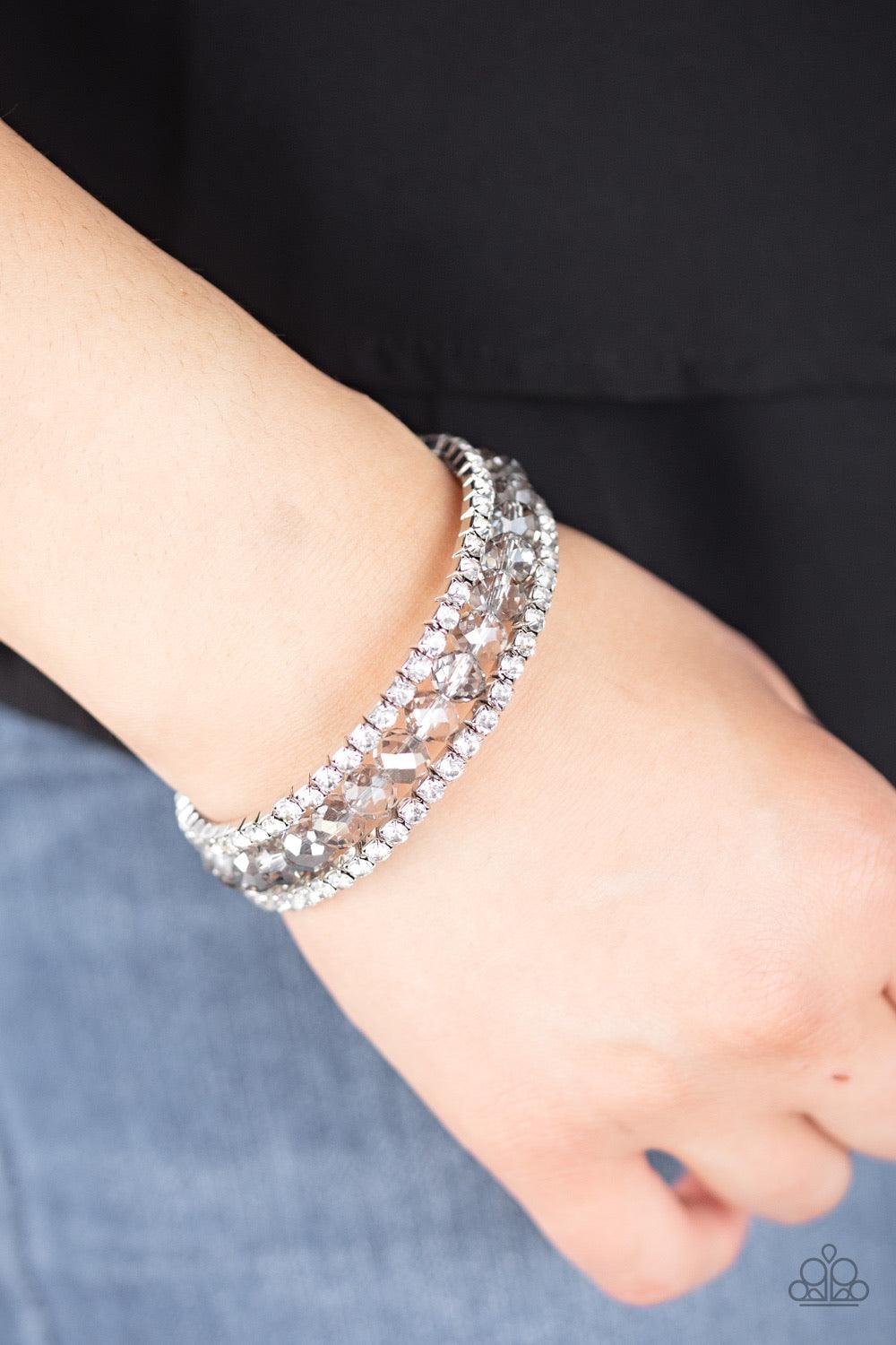 Paparazzi Accessories Glam-ified Fashion - Silver A refined collection of white rhinestone encrusted frames and smoky crystal-like beads are threaded along a coiled wire, creating a timeless infinity wrap style bracelet around the wrist. Sold as one indiv