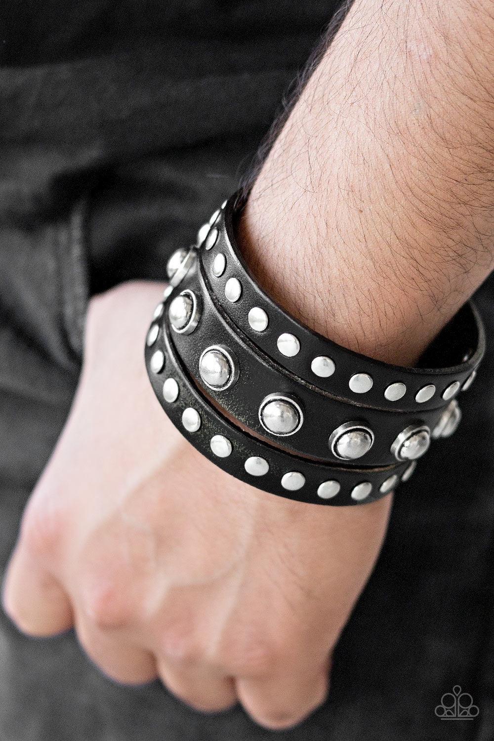 Paparazzi Accessories Win Your Spurs - Black Round and flat silver studs are studded across the front of a thick black leather band that has been spliced into three bands. Features an adjustable snap closure. Jewelry