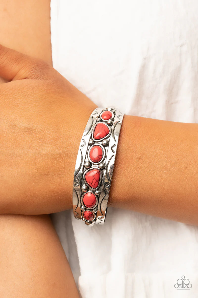 Paparazzi Accessories Saguaro Suitan - Red An asymmetrical collection of fiery red stones are encrusted across the studded center of a rustic silver cuff stamped in tribal inspired textures, resulting in an authentic centerpiece around the wrist. Sold as