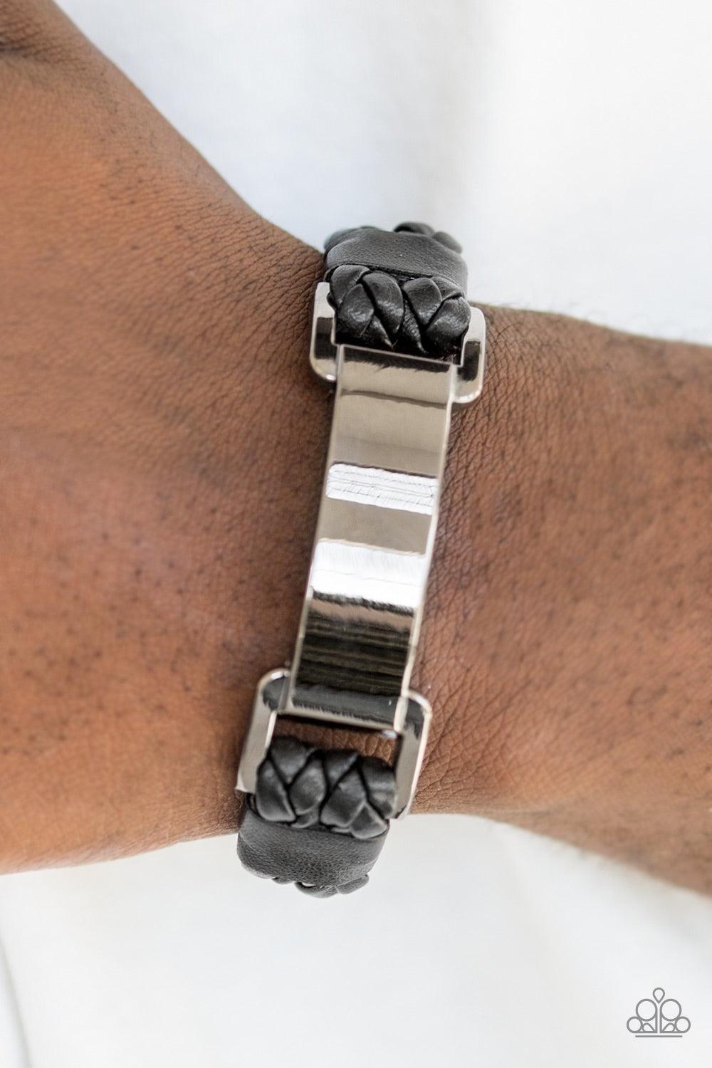 Paparazzi Accessories Traffic Jam - Black Braided black leather bands loop through a glistening gunmetal frame. The shiny leather strands secure the frame in place across the wrist for an urban look. Features an adjustable sliding knot closure. Jewelry
