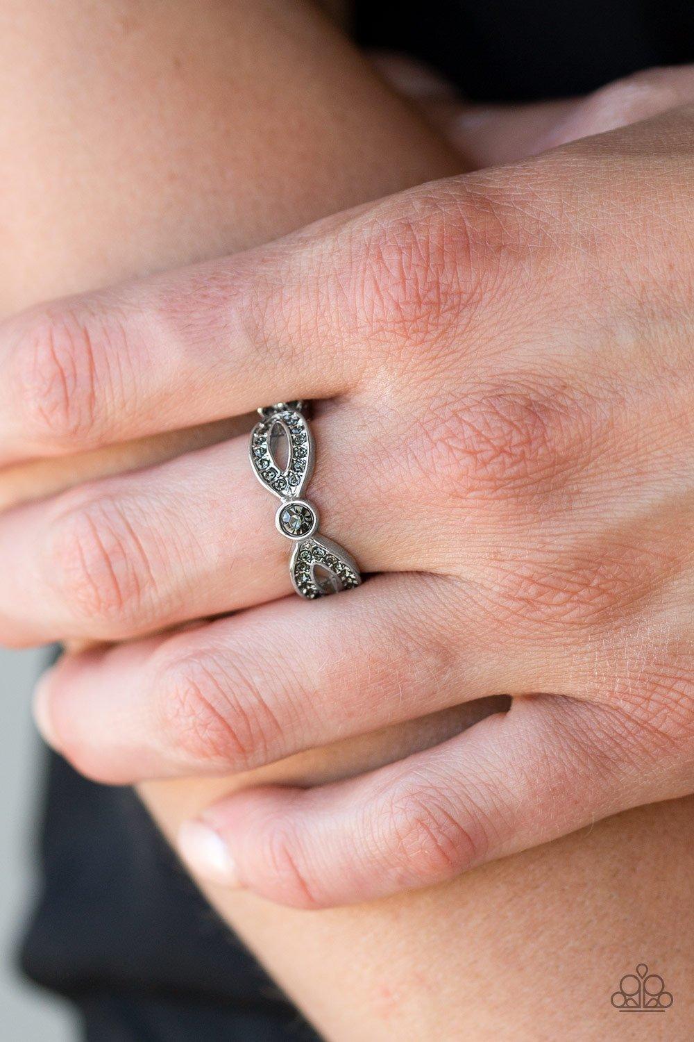Paparazzi Accessories Extra Side of Elegance - Silver Encrusted in smoky rhinestones, glistening silver ribbons loop away from a dazzling rhinestone center for a refined look. Features a dainty stretchy band for a flexible fit. Sold as one individual ring