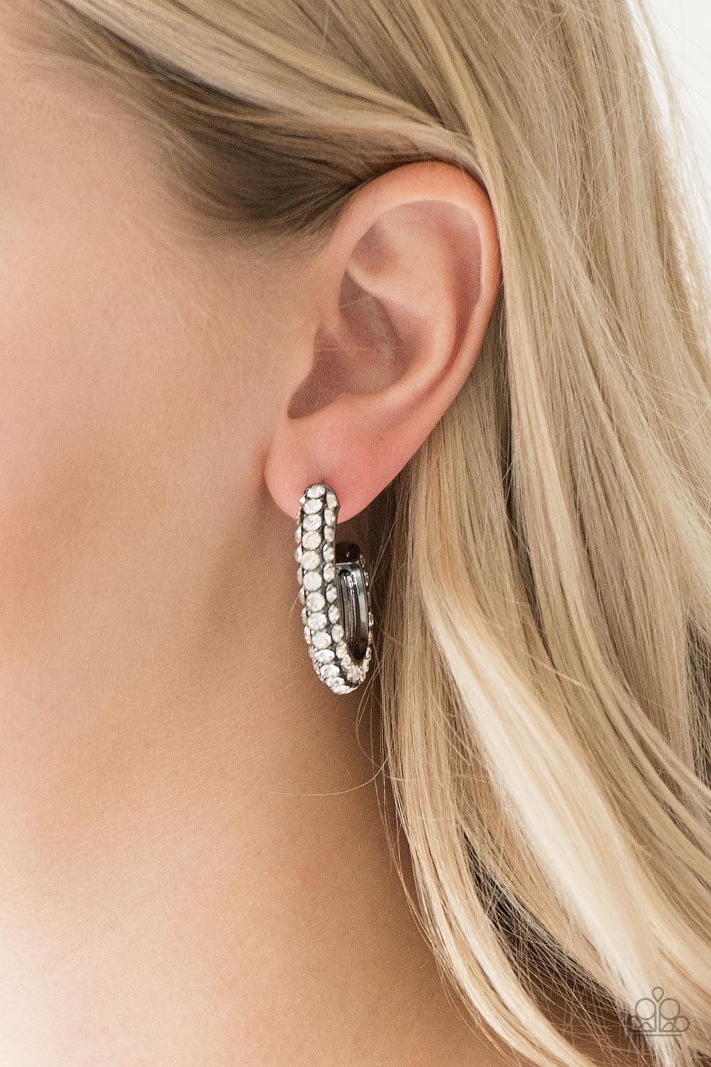 Paparazzi Accessories Don’t Mind The Stardust - Black As if rolled in glitter, a shimmery gunmetal hoop is encrusted in row after row of sparkling white rhinestones for a show-stopping look. Earring attaches to a standard post fitting. Hoop measures 1" in