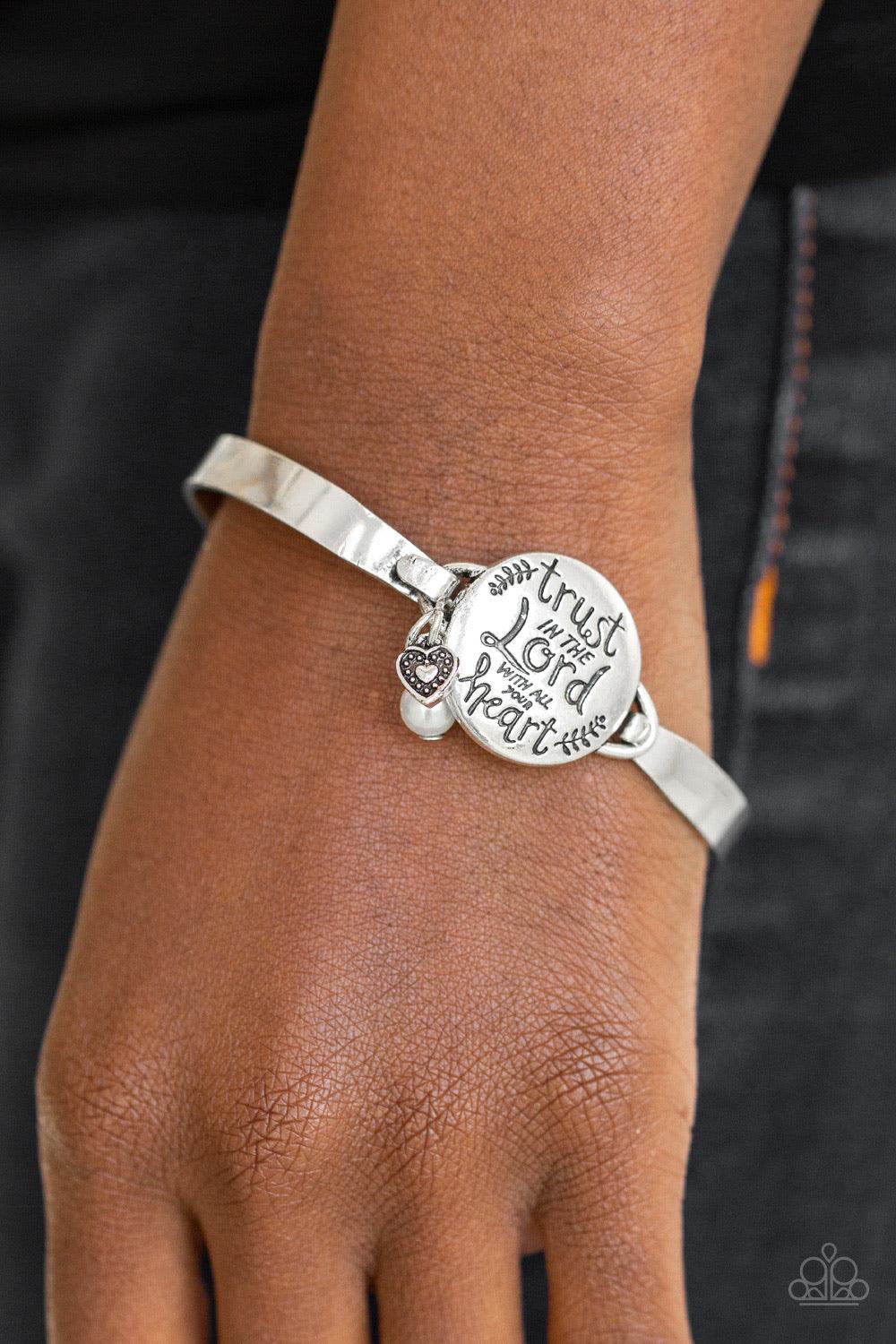 Paparazzi Accessories Total Trust ~White Infused with a classic white pearl and dainty silver heart charm, shiny silver bars curl around the wrist and attach to a round centerpiece stamped in the inspiration phrase, "Trust In The Lord With All Your Heart"