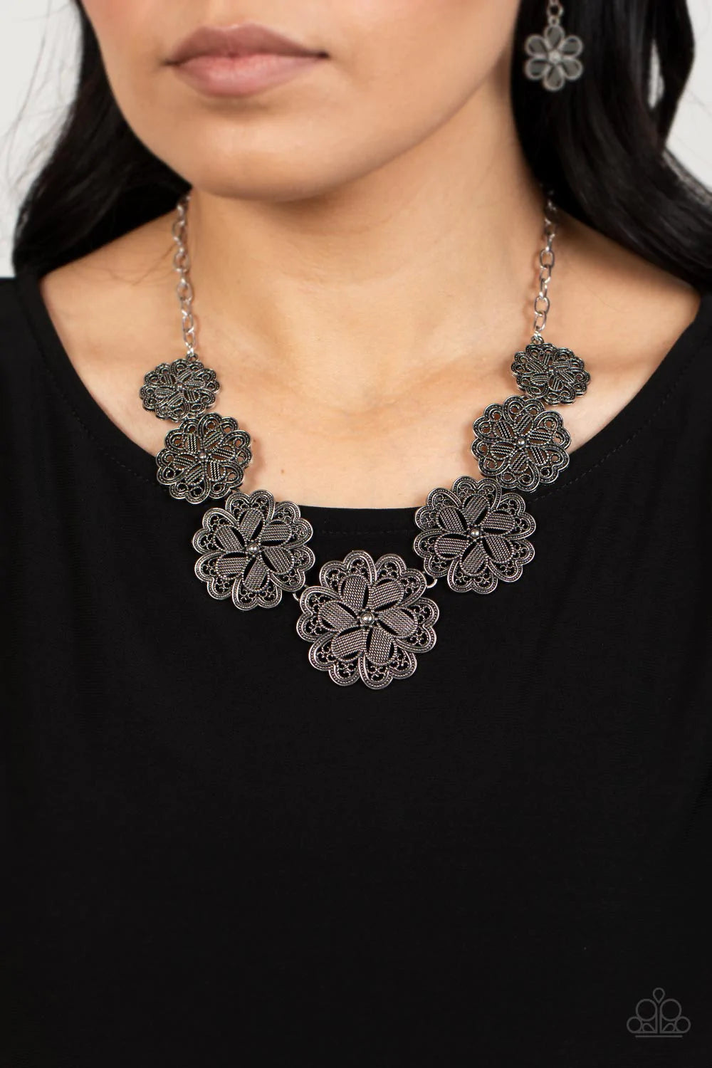 Paparazzi Accessories Basketful of Blossoms - Silver Featuring metallic wicker-like patterns, stacks of teardrop and heart shaped filigree-filled silver petals delicately link into a decorative row of flowers. The floral frames gradually increase in size