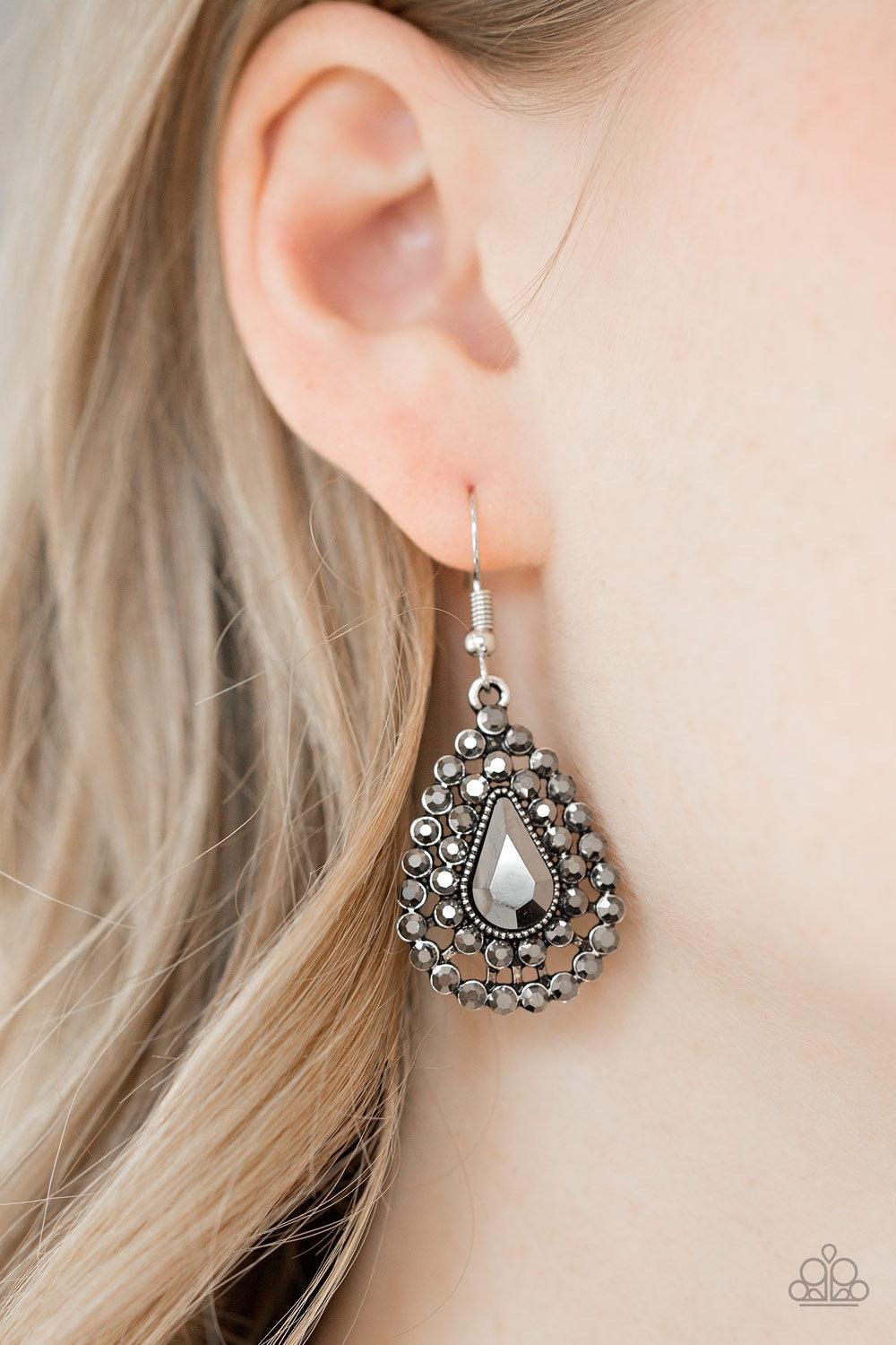Paparazzi Accessories Diamond Dazzle - Silver Glittery hematite rhinestones spin around a teardrop gem, coalescing into a dazzling lure. Earring attaches to a standard fishhook fitting. Jewelry