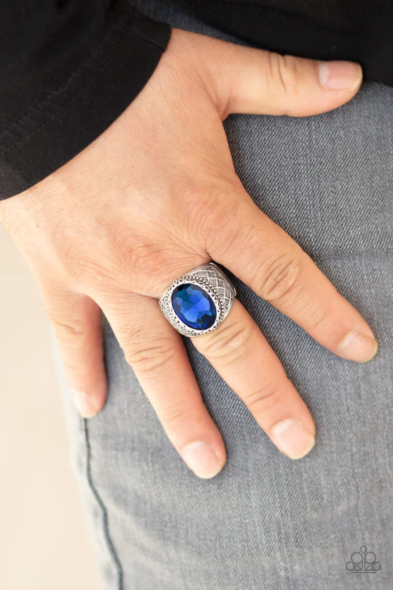 Paparazzi Accessories Pro Bowl - Blue An oval blue rhinestone is pressed into the center of a thick silver band embossed in a crisscrossed texture for a regal look. Features a stretchy band for a flexible fit. Sold as one individual ring.