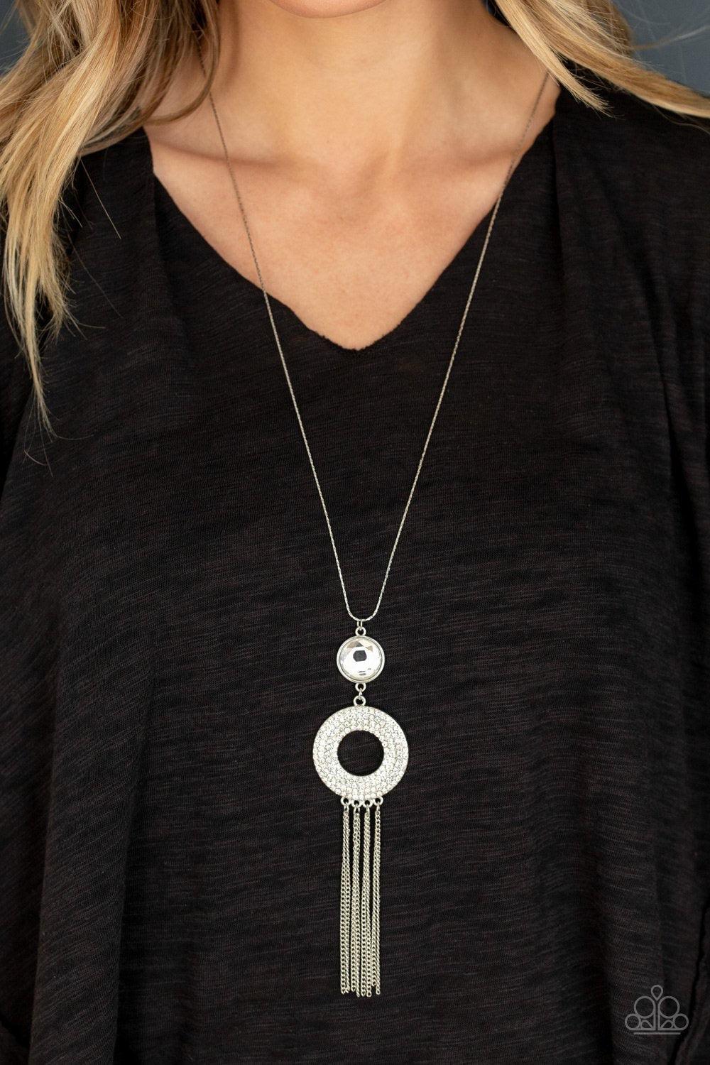 Paparazzi Accessories Sassy As They Come - White A large rounded rhinestone dangles above a glistening white rhinestone encrusted ring which swings from the bottom of a lengthened silver chain, creating a glamorous pendant. Rounded silver snake chains str