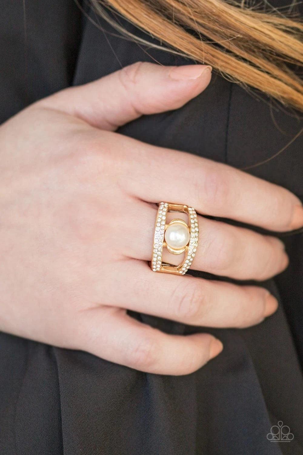 Paparazzi Accessories Bank Run - Gold Encrusted in glassy white rhinestones two glistening gold ribbons arc across the finger. Infused with a sleek gold fitting, a classic white pearl is pressed into the center of the bands for a refined finish. Features