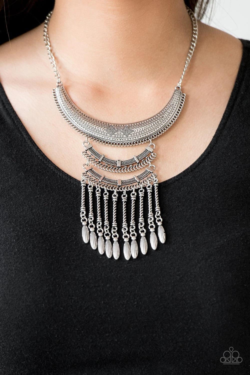 Paparazzi Accessories Eastern Empress - Silver Stamped and embossed in tribal inspired patterns, three silver plates connect down the chest, creating a fiercely stacked pendant. Attached to twisted silver rods, ornate silver beads swing from the bottom of