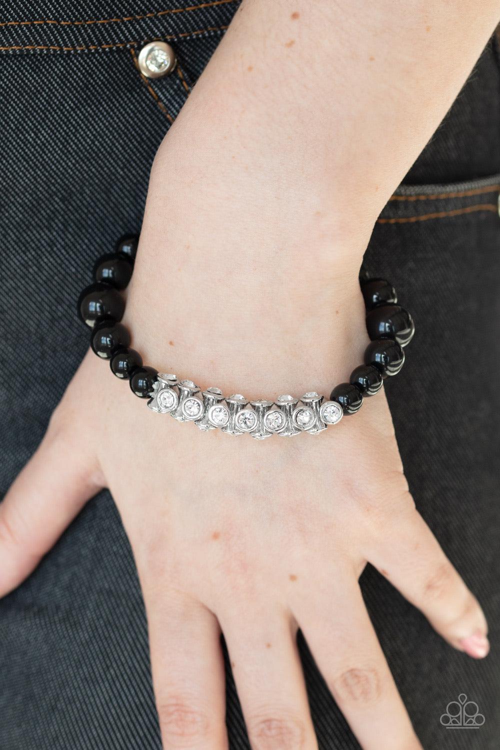 Paparazzi Accessories Traffic Stopping Sparkle - Black A collection of black beads and white rhinestone dotted silver frames are threaded along a stretchy band around the wrist, creating a sparkling centerpiece. Sold as one individual bracelet. Jewelry