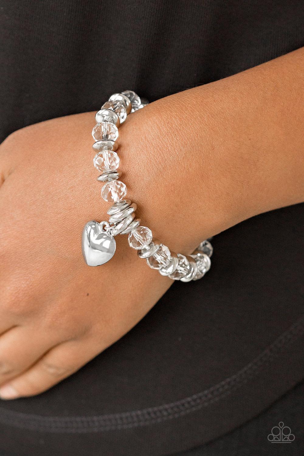 Paparazzi Accessories Need I Say AMOUR? - White Sparkling crystal-like beads and shimmery silver accents are threaded along a stretchy band. An oversized silver heart charm swings from the wrist for a whimsical finish. Sold as one individual bracelet. Jew
