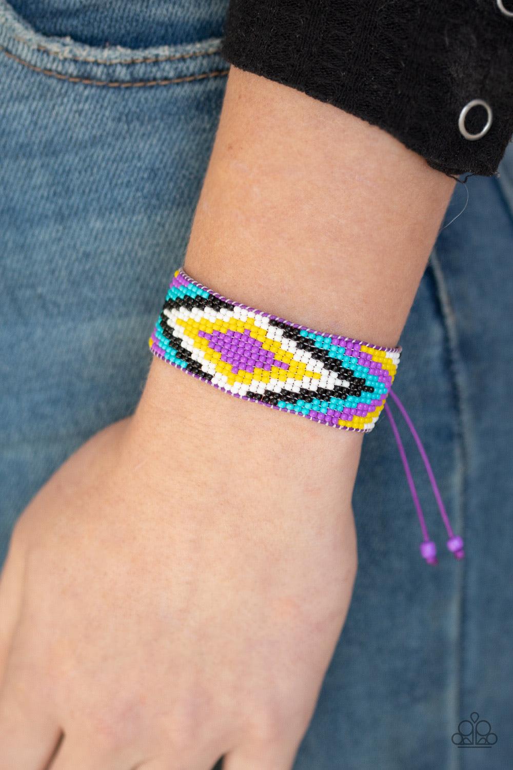 Paparazzi Accessories Beautifully Badlands - Purple Threaded along invisible thread, a dainty collection of purple, blue, black, white, and yellow seed beads weave into a colorful textile pattern across the wrist for a tribal inspired look. Features an ad