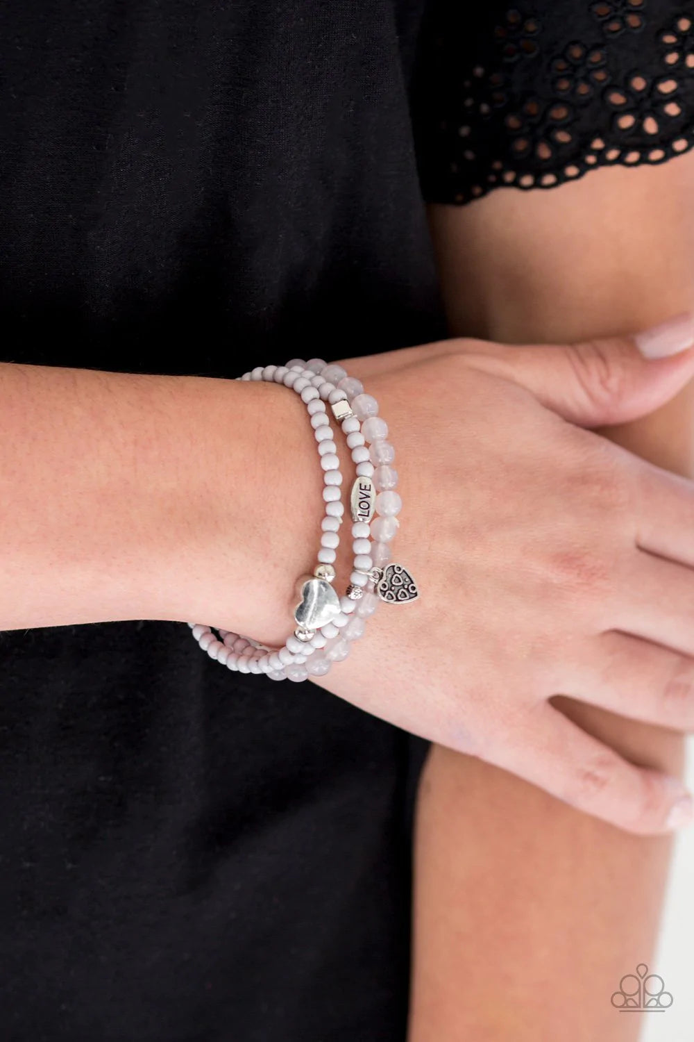 Paparazzi Accessories Really Romantic - Silver An array of glassy and polished gray beads are threaded along stretchy bands. Infused with silver accents, a collection of silver heart charms and a bead spelling out the word, "love", adorn the beaded strand