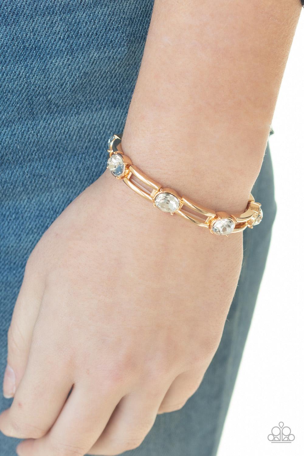 Paparazzi Accessories Flash or Credit? - Gold A glittery collection of white rhinestones and airy rectangular gold frames are threaded along stretchy bands around the wrist for a glitzy look. Sold as one individual bracelet. Jewelry