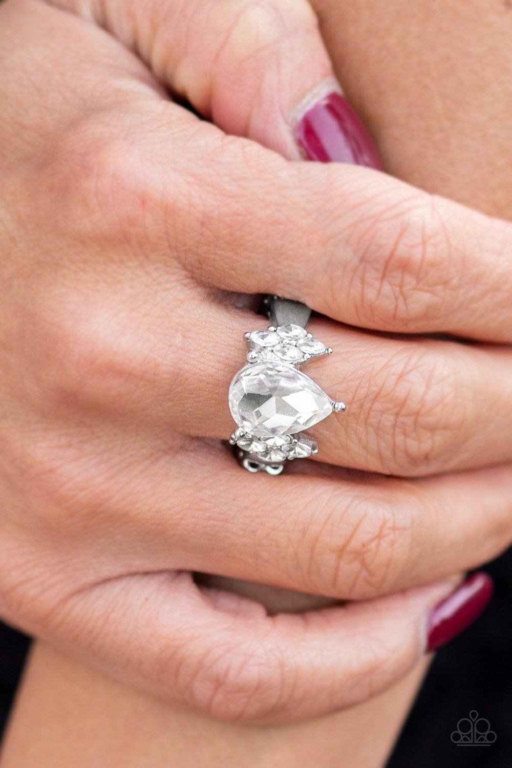 Paparazzi Accessories Yas Queen - White A dramatic white teardrop gem is pressed into the center of a dainty silver band. Featuring regal marquise-cuts, dainty white rhinestones flank the sparkling teardrop center for a glamorous finish. Features a dainty