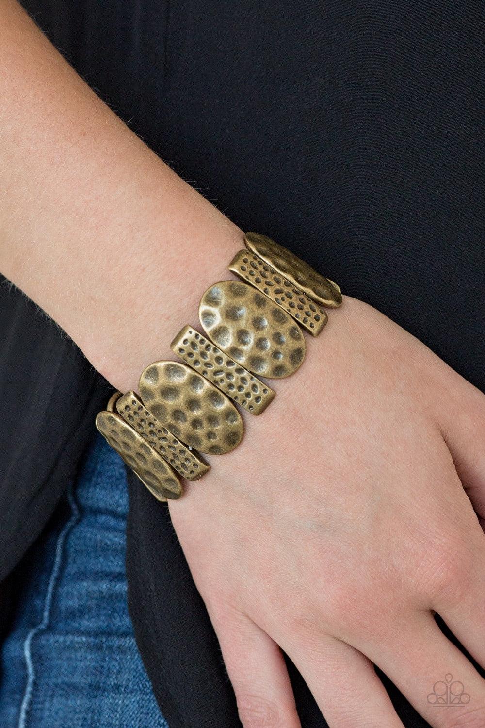 Paparazzi Accessories Cave Cache - Brass Delicately hammered in antiqued detail, round and rectangular shaped frames are threaded along stretchy bands, creating a bold tribal look around the wrist. Jewelry