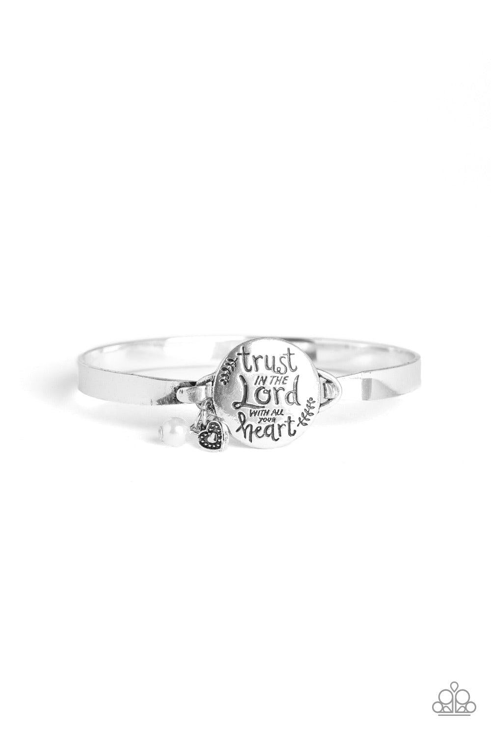 Paparazzi Accessories Total Trust ~White Infused with a classic white pearl and dainty silver heart charm, shiny silver bars curl around the wrist and attach to a round centerpiece stamped in the inspiration phrase, "Trust In The Lord With All Your Heart"