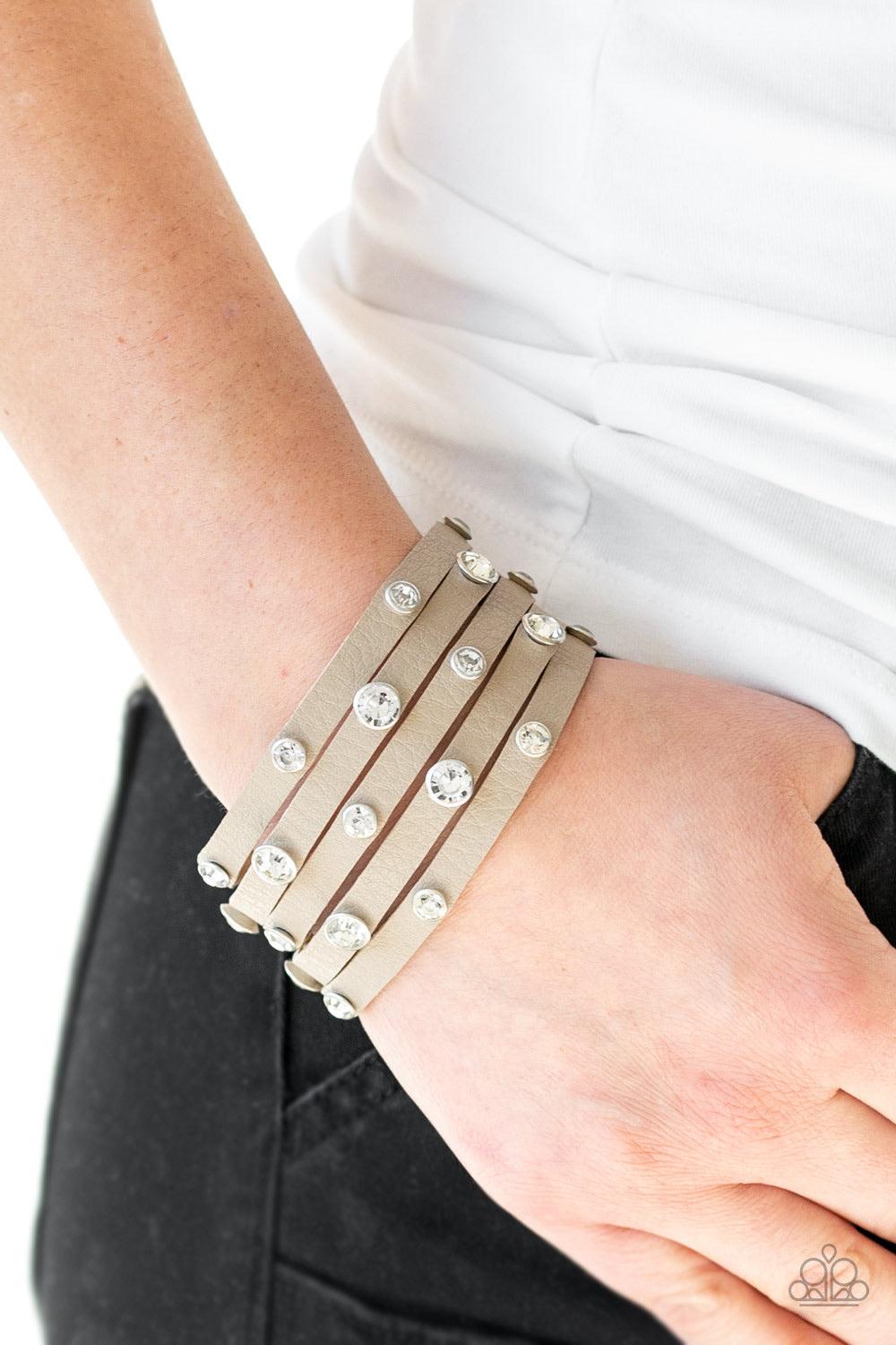 Paparazzi Accessories Rhinestone Reputation - Brown Dotted with glassy white rhinestones, a thick brown leather band has been spliced into five glittery strands around the wrist for a sassy look. Features an adjustable snap closure. Sold as one individual