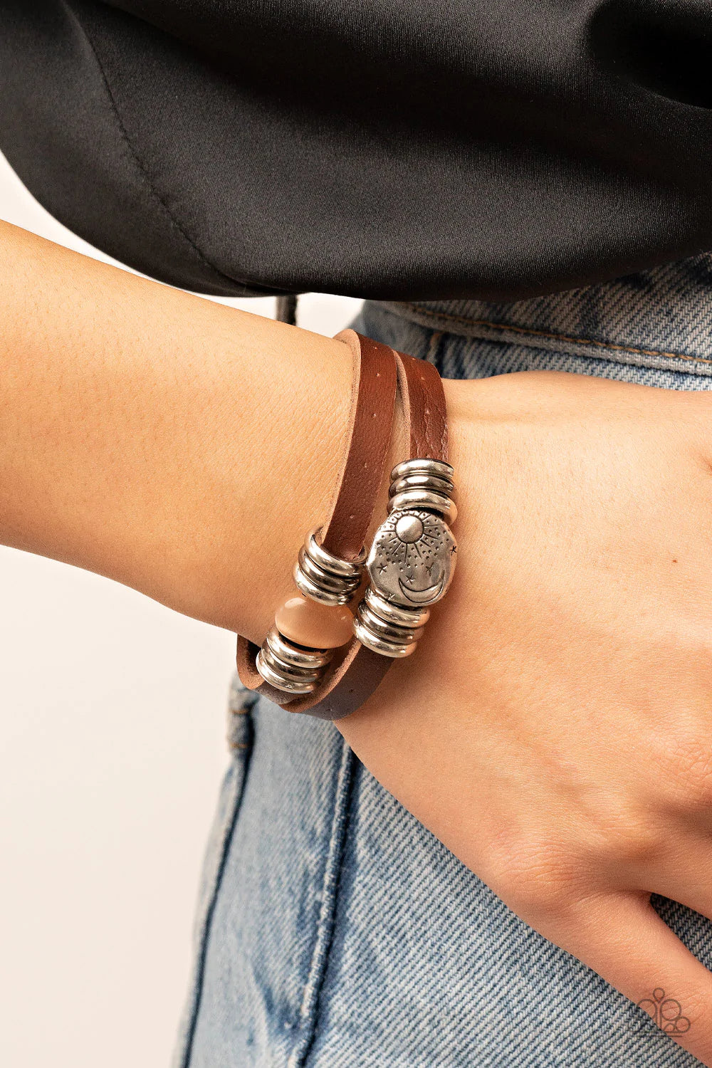 Paparazzi Accessories All Willy-Nilly - Orange Infused with trios of silver and gunmetal rings, a glassy orange cat's eye stone and hammered silver disc stamped in a starry sun and moon pattern adorns layered brown leather bands around the wrist for a sea