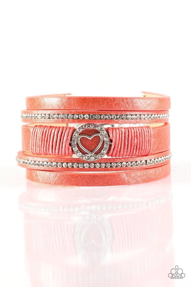 Paparazzi Accessories It Takes Heart - Orange Brushed in a metallic shimmer, strips of orange leather are encrusted in alternating rows of glittery white rhinestones. Orange cording knots around the centermost strand, securing a sparkling heart frame in p