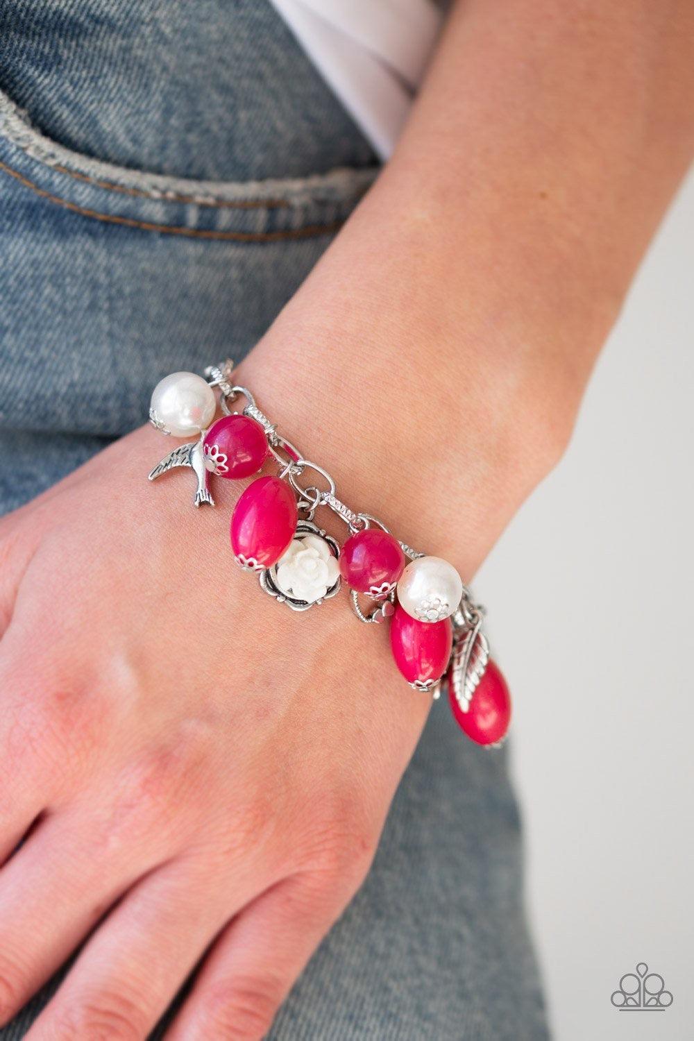 Paparazzi Accessories Love Doves - Pink Gorgeous pearls, shiny pink beading, and a collection of shiny silver charms, including a bird and a feather, dance around the wrist in a whimsical fashion. Features an adjustable clasp closure. Sold as one individu