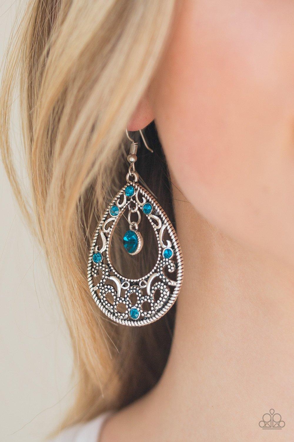 Paparazzi Accessories Gotta Get That Glow - Blue Glistening and studded silver filigree swirls along a shimmery silver frame radiating with glittery blue rhinestones. A sparkling blue rhinestone swings from the top of the frame for a refined finish. Earri