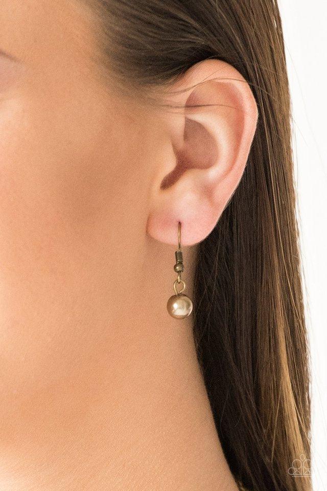 Paparazzi Accessories Shipwreck Style - Brass Brushed in an antiqued shimmer, mismatched brass hoops, brass pearls, and dainty brass beads swing from the bottom of a bold brass chain below the collar for a refined look. Features an adjustable clasp closur