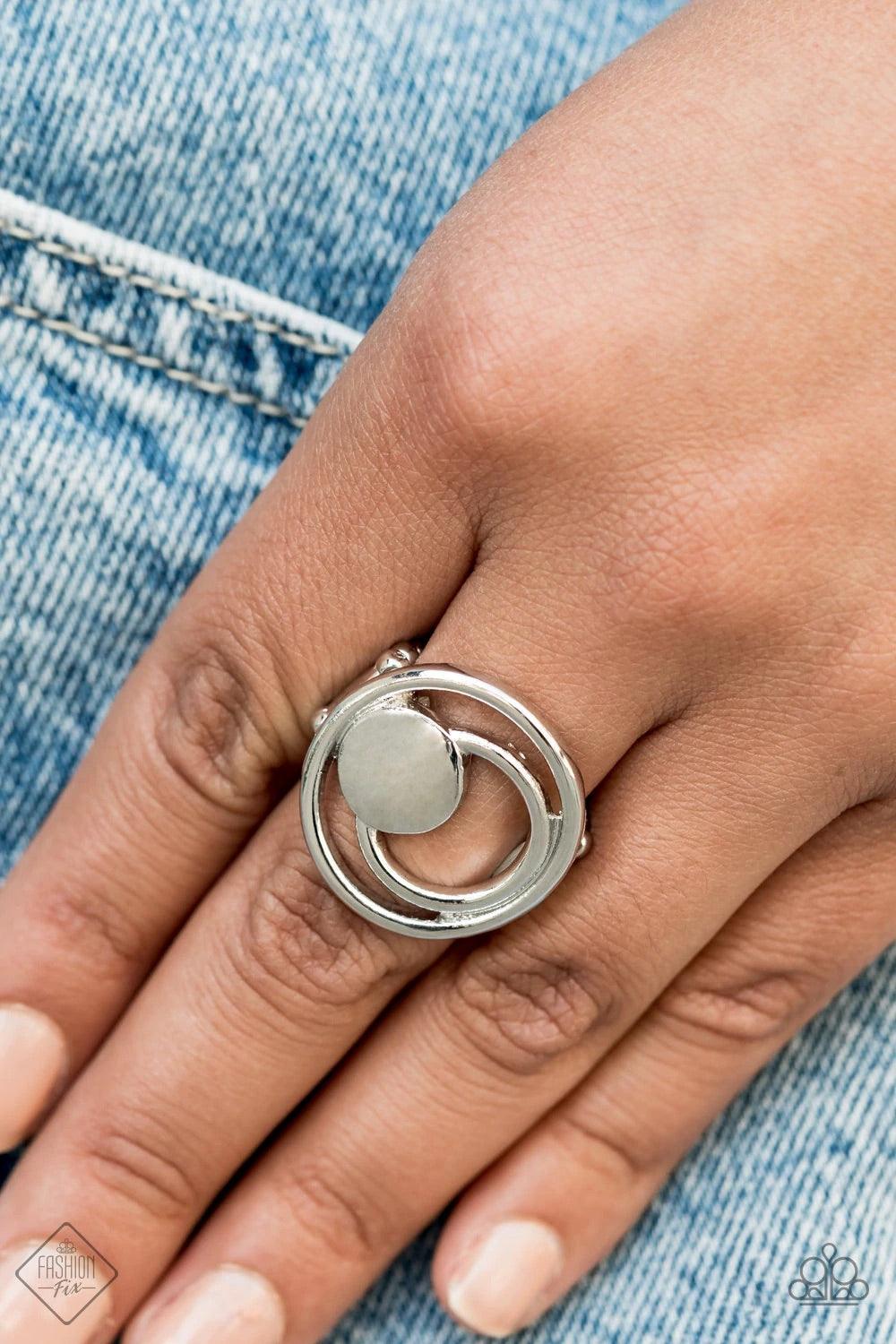 Paparazzi Accessories Edgy Eclipse - Silver A solid silver disc and airy silver hoops eclipse across the finger, delicately coalescing into an edgy offset frame. Features a stretchy band for a flexible fit. Sold as one individual ring. Jewelry