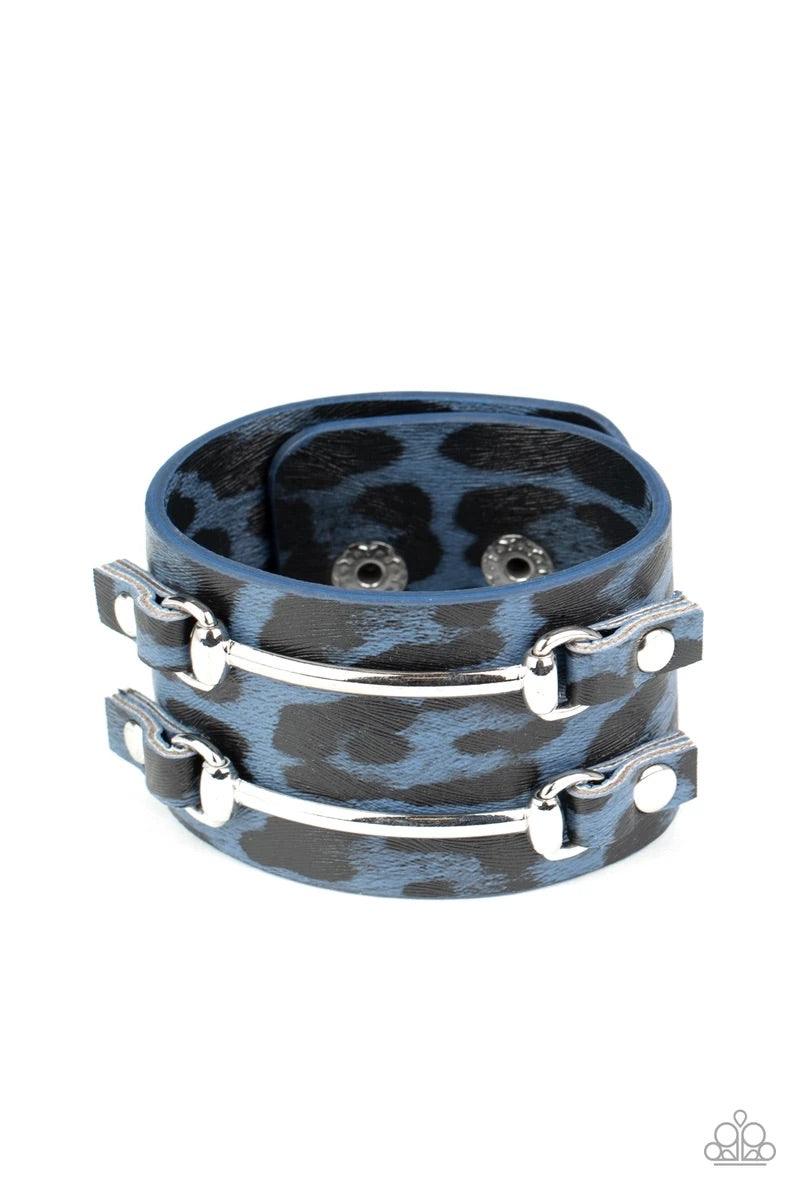 Paparazzi Accessories Safari Scene - Blue Two arcing silver bars are studded in place across the front of a thick leather band painted in blue and black cheetah print for a wild look. Features an adjustable snap closure. Sold as one individual bracelet. J