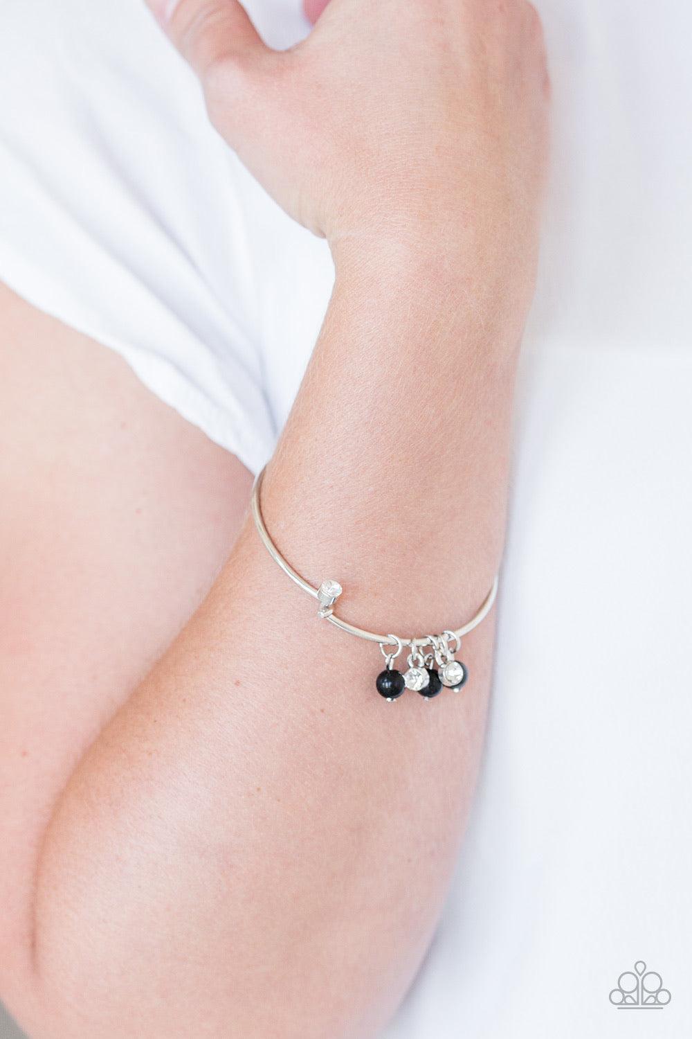 Paparazzi Accessories Marine Melody - Black Glassy black beads and glittery white rhinestones slide along a dainty silver wire infused with a rhinestone encrusted fitting, creating a versatile adjustable like bangle. Features a hinged closure. Jewelry