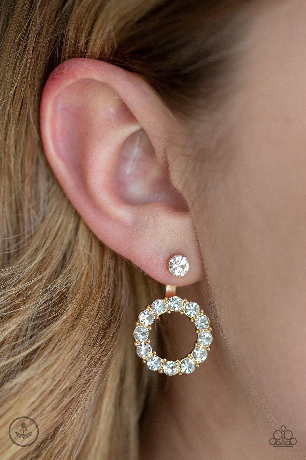 Paparazzi Accessories Diamond Halo - Gold A solitaire white rhinestone attaches to a double-sided post, designed to fasten behind the ear. Encrusted in a ring of glassy white rhinestones, the glittery hoop peeks out beneath the ear for a glamorous look. E