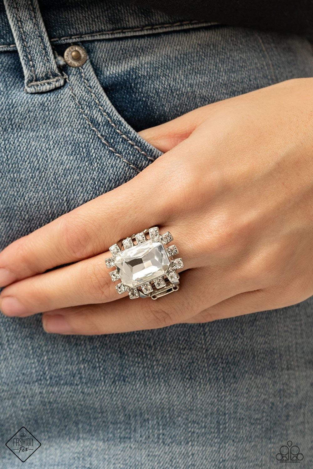 Paparazzi Accessories Galactic Glamour - White Featuring dainty silver square fittings, an explosion of glassy white rhinestones fans out from a dramatically oversized emerald cut rhinestone center, creating a stellar centerpiece atop the finger. Features