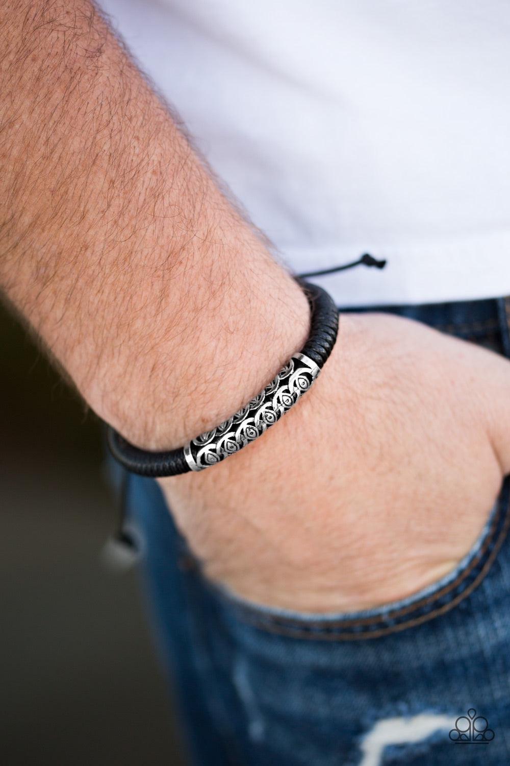 Paparazzi Accessories Island Escape - Black Black cording knots around a leather cord, creating a sleek urban piece around the wrist. An ornate silver bead slides along the colorful strand, creating a bold centerpiece. Features an adjustable sliding knot