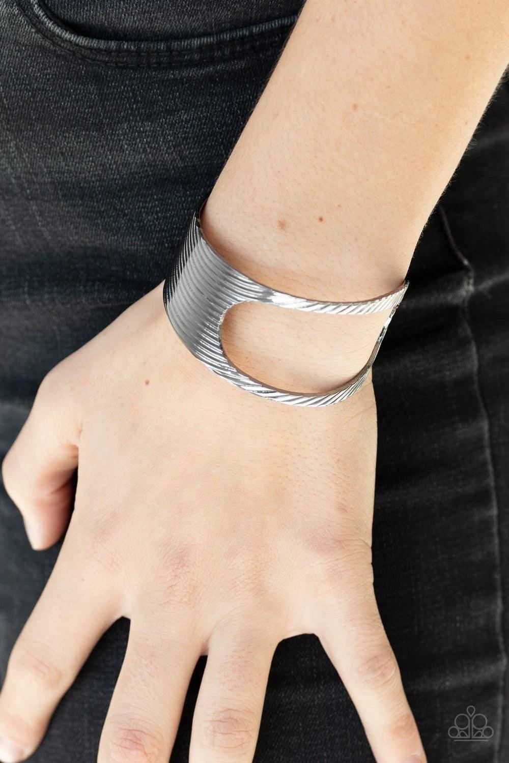 Paparazzi Accessories What GLEAMS Are Made Of - Black Stamped in a slanted linear pattern, a glistening gunmetal cuff featuring an airy asymmetrical cutout wraps around the cuff for a bold industrial look. Sold as one individual. Jewelry