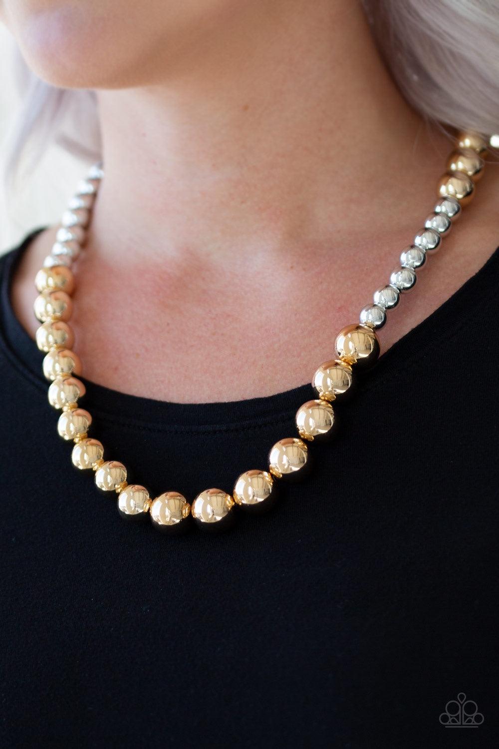Paparazzi Accessories Power To The People - Gold Varying in size, glistening gold and shimmery silver beads drape below the collar in a dramatically asymmetrical fashion. Features an adjustable clasp closure. Jewelry