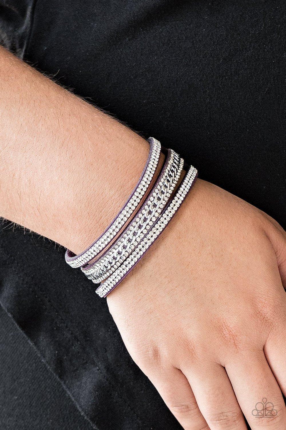 Paparazzi Accessories Rollin’ In Rhinestones - Purple Rows of glassy white rhinestones and a shimmery silver chain are encrusted along vibrant purple suede bands for a sassy look. Features an adjustable snap closure.Sold as one individual bracelet. Jewelr