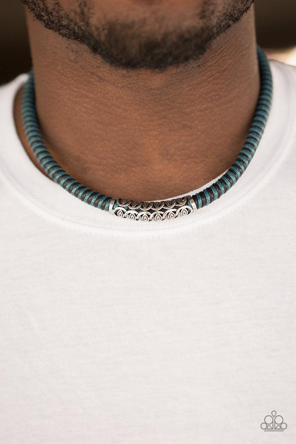 Paparazzi Accessories The Mainland - Blue Blue and black cording knots around a leather cord, creating a colorful urban piece below the collar. An ornate silver bead slides along the colorful strand, creating a bold centerpiece. Features a button loop clo