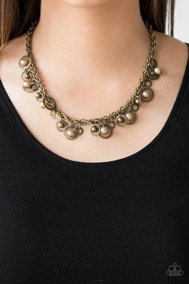 Paparazzi Accessories Shipwreck Style - Brass Brushed in an antiqued shimmer, mismatched brass hoops, brass pearls, and dainty brass beads swing from the bottom of a bold brass chain below the collar for a refined look. Features an adjustable clasp closur