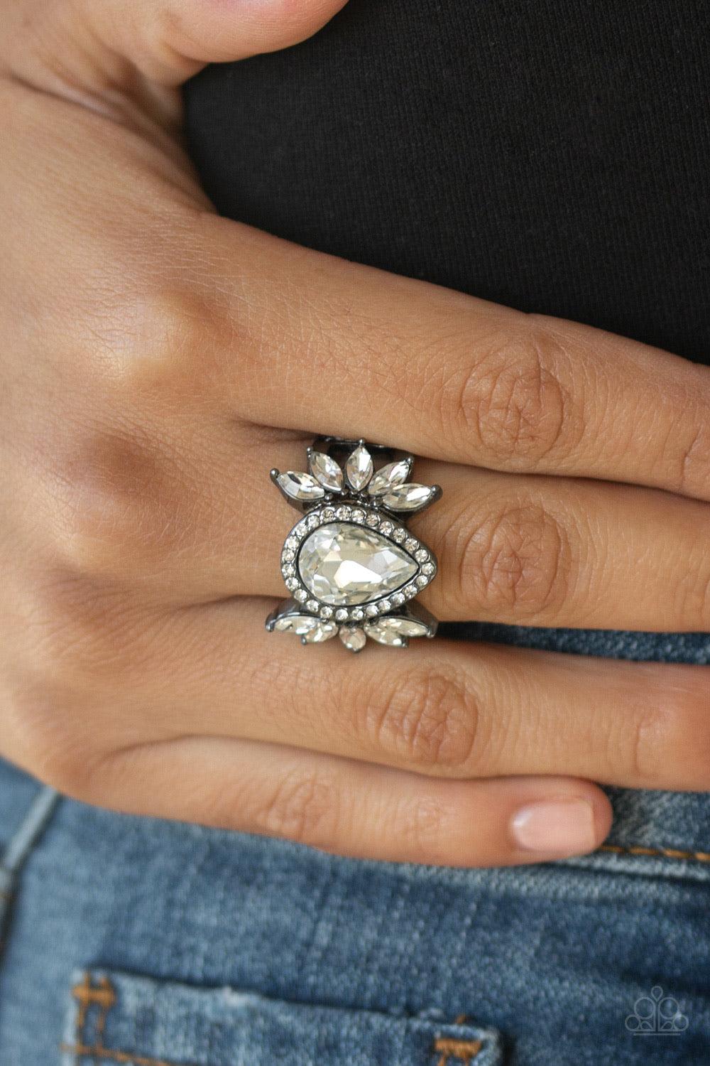 Paparazzi Accessories Really Regal - Black An oversized white teardrop rhinestone is nestled between two gunmetal frames radiating with fans of white marquise-style rhinestones. Features a stretchy band for a flexible fit. Jewelry