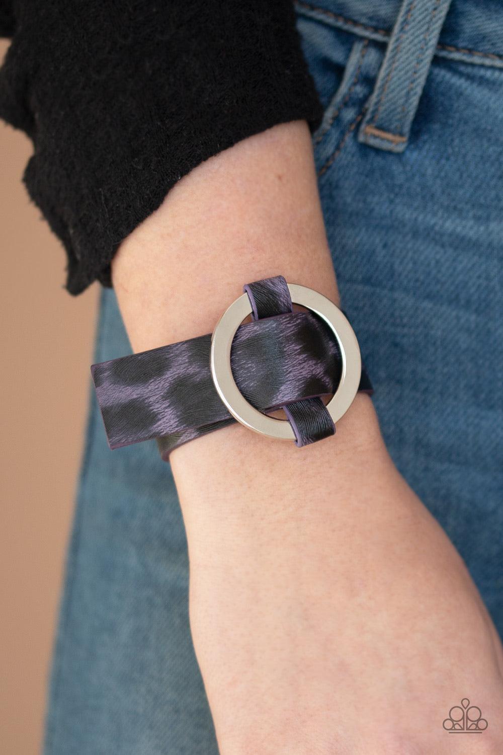 Paparazzi Accessories Jungle Cat Couture - Purple Featuring a shiny purple cheetah pattern, a textured piece of leather loops through the center of a shimmery silver hoop for a sassy urban look. Features an adjustable belt loop closure. Sold as one indivi