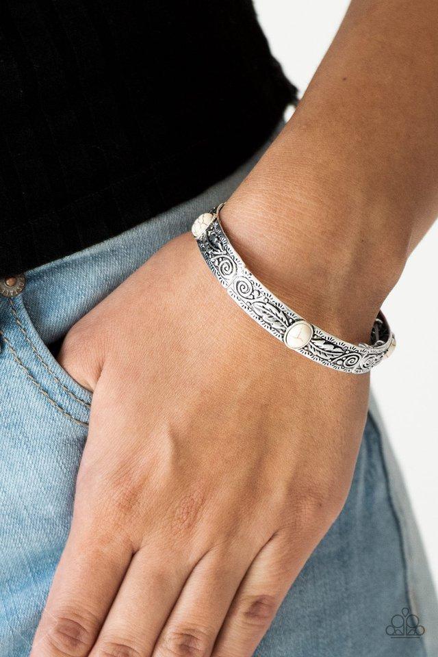 Paparazzi Accessories Wild West Story - White Embossed in swirling silver and feather like detail, antiqued silver frames are threaded along stretchy bands around the wrist. Refreshing white stones adorn the centers of the Southwestern frames for a season