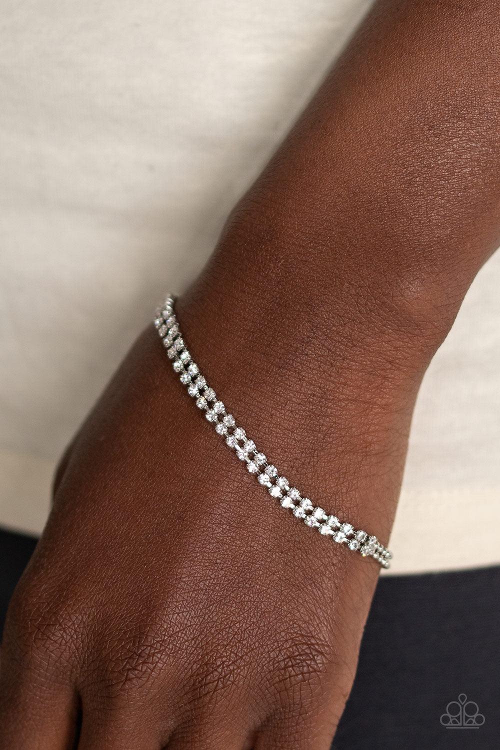 Paparazzi Accessories All Dolled Up - White Delicately coalescing into a solitaire centerpiece, two dainty silver ball chains attach to two rows of glassy white rhinestones across the wrist for a timeless look. Features an adjustable clasp closure. Jewelr