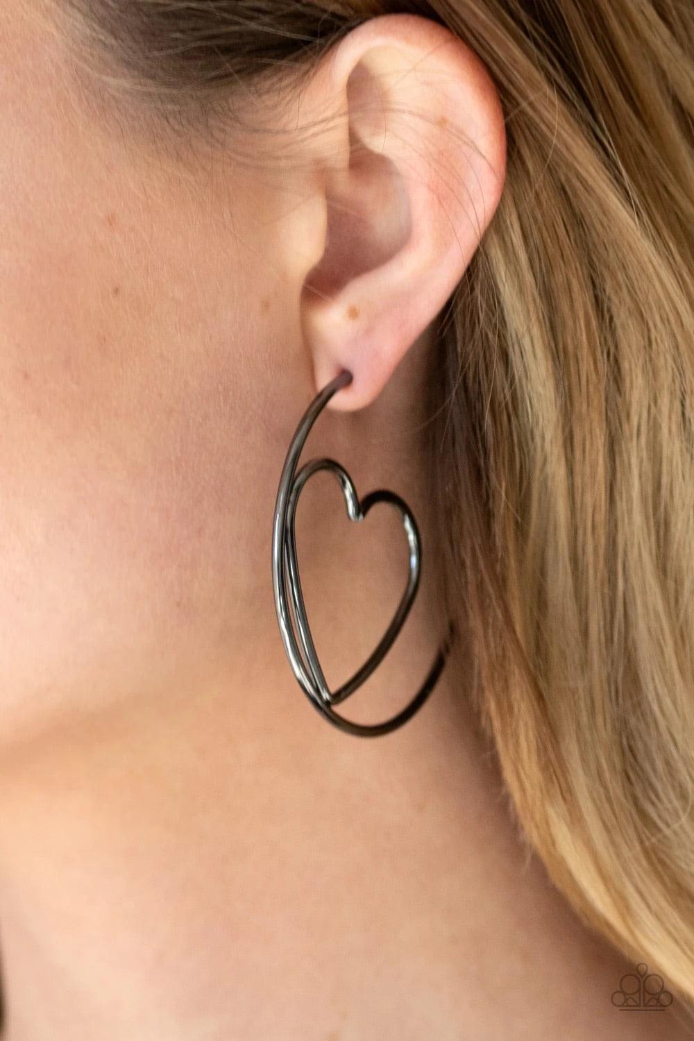 Paparazzi Accessories Love At First Bright - Black Glistening gunmetal wire delicately bends into an airy heart frame inside a classic gunmetal hoop, creating a flirtatious display. Earring attaches to a standard post fitting. Hoop measures approximately