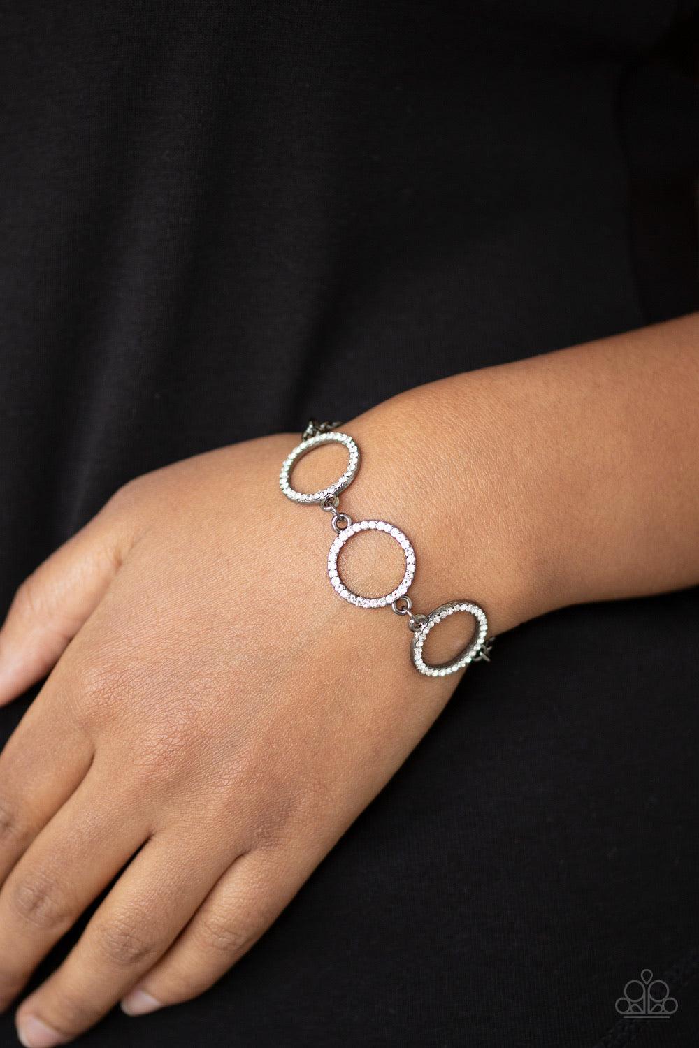 Paparazzi Accessories Dress The Part - Black Encrusted in glassy white rhinestones, three glittery gunmetal rings link across the wrist for a glamorous look. Features an adjustable clasp closure. Sold as one individual bracelet. Jewelry