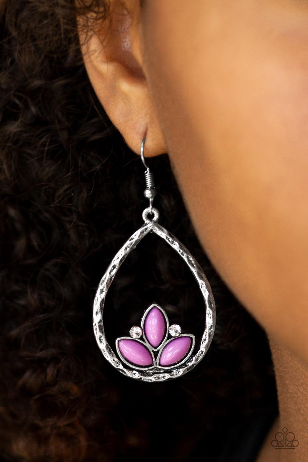 Paparazzi Accessories Lotus Laguna - Purple Shiny purple beads adorn the bottom of a hammered silver teardrop, coalescing into a whimsical lotus pattern. Dainty white rhinestones flank the shiny beads for a refined finish. Earring attaches to a standard f