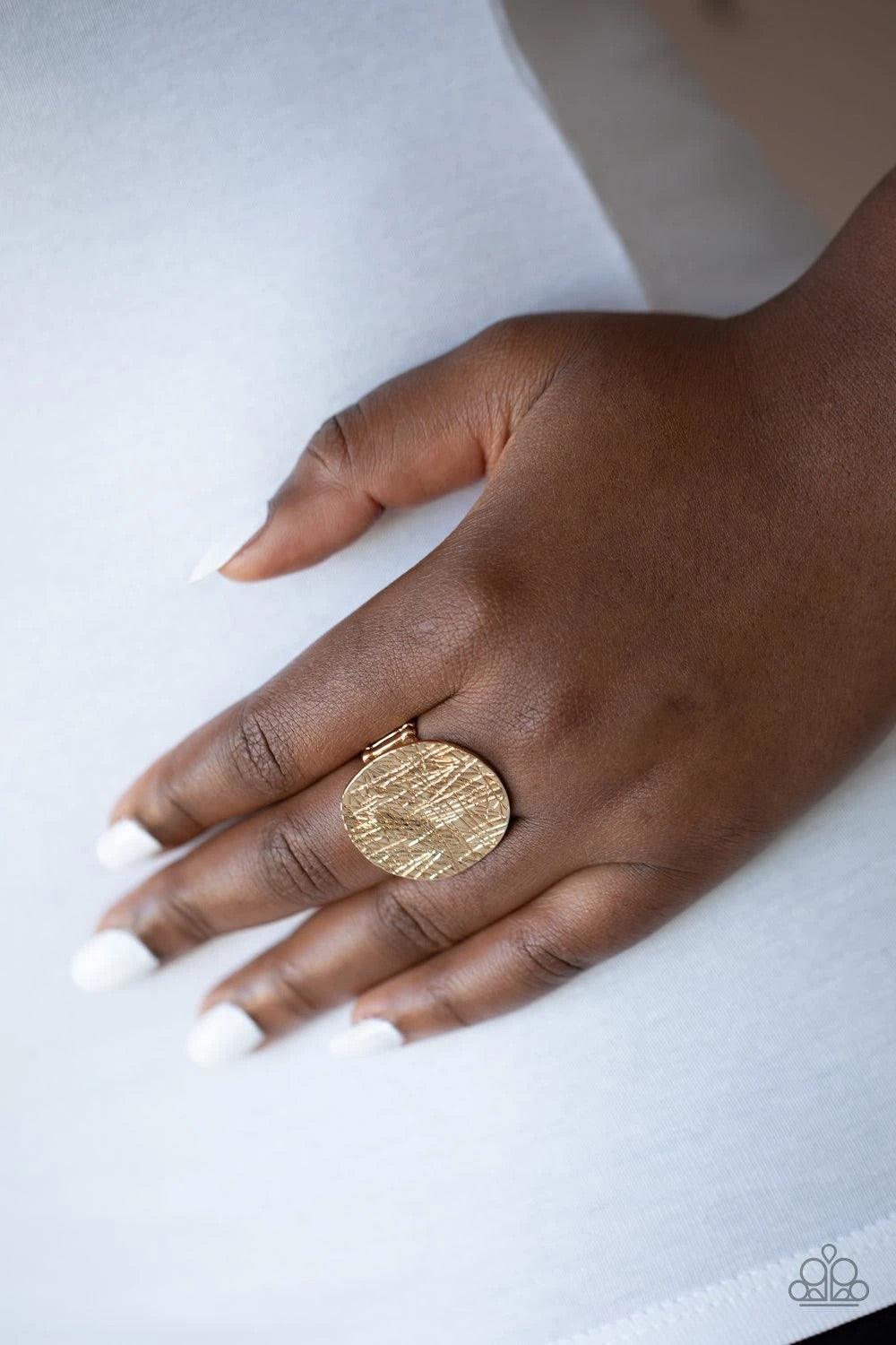 Paparazzi Accessories Lined Up - Gold An oversized gold disc is etched in crisscrossing textures and hammered into light-catching ripples as it sits atop the finger unapologetically. Features a stretchy band for a flexible fit. Sold as one individual ring