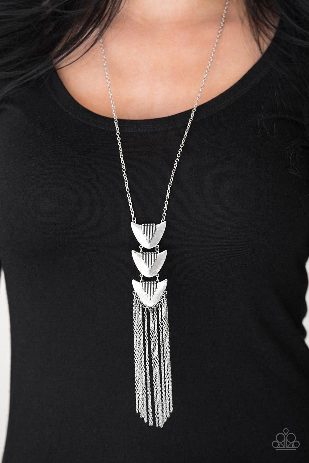 Paparazzi Accessories Paradise Prowess - Silver Radiating in linear textures, antiqued silver plates connect down the chest, creating a tribal inspired pendant. Glistening silver chains swing from the bottom of the stacked pendant, adding a whimsical tass