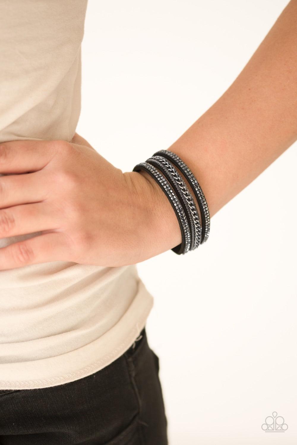 Paparazzi Accessories Unstoppable - Black Glittery hematite rhinestones and shimmery gunmetal chains are encrusted along strands of black suede, creating a mishmash of sassy shimmer around the wrist for a fierce look. Features an adjustable snap closure.