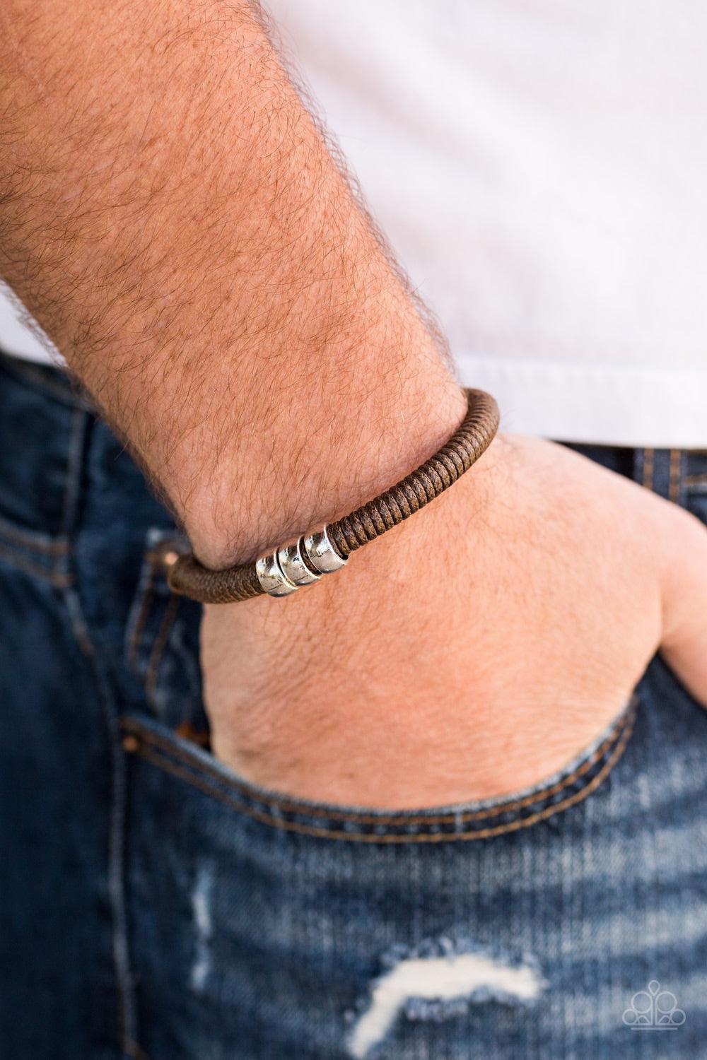 Paparazzi Accessories One For The Trail - Brown Shiny brown twine wraps around a black cord, creating an urban look around the wrist. Shiny silver beads slide along the cording for a rugged finish. Features an adjustable sliding knot closure. Jewelry